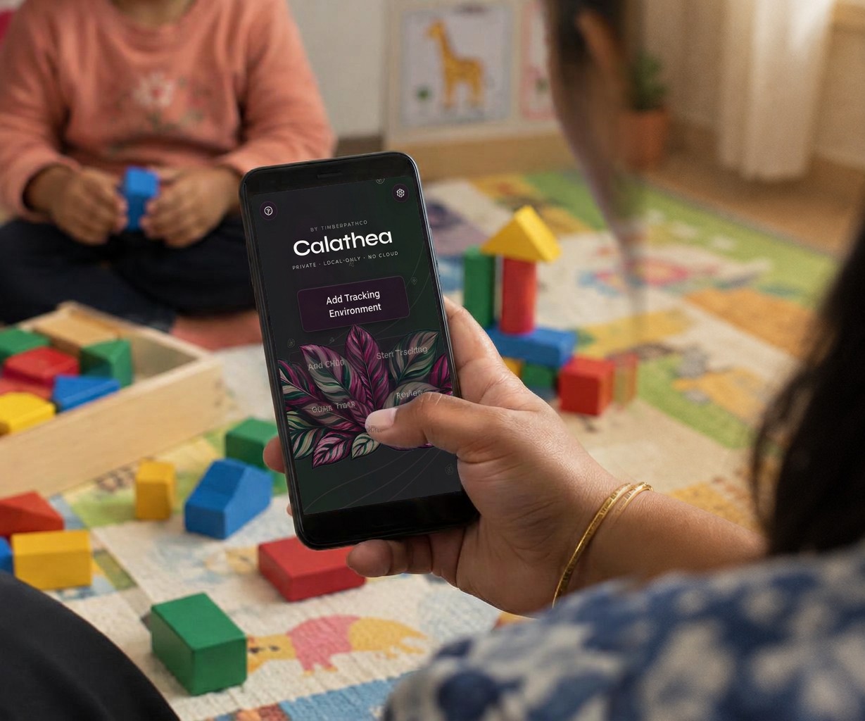 A therapist taps Calathea on her phone beside a child playing with blocks